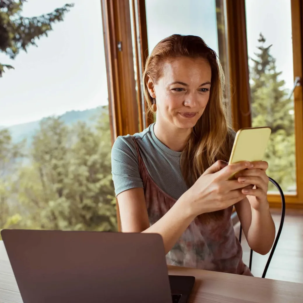 Close up of a mid adult woman using a phone while spending time in her cabin in the woods