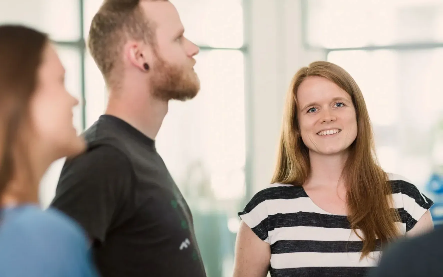 Eine Gruppe von Personen steht in einem Büro und diskutiert über Magento-Integrationsprojekte.