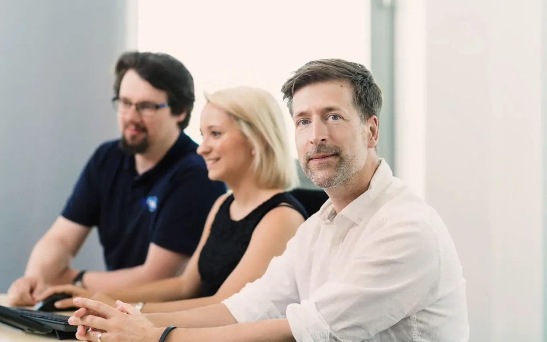 Eine Gruppe von Personen steht in einem Büro und diskutiert ein Projekt.