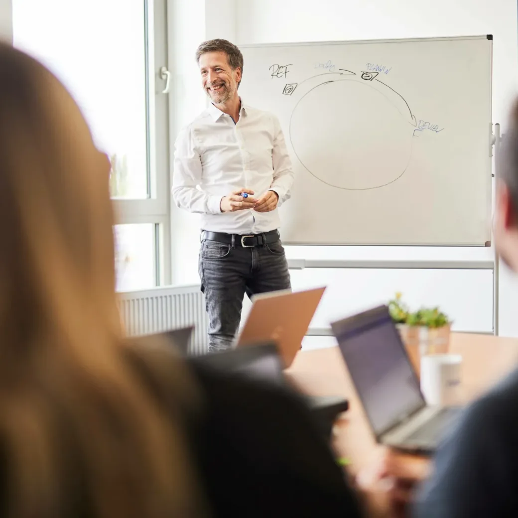 A man gives a presentation in front of a whiteboard