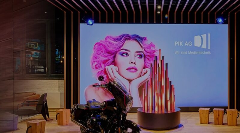 Vor einem großen Bildschirm mit 