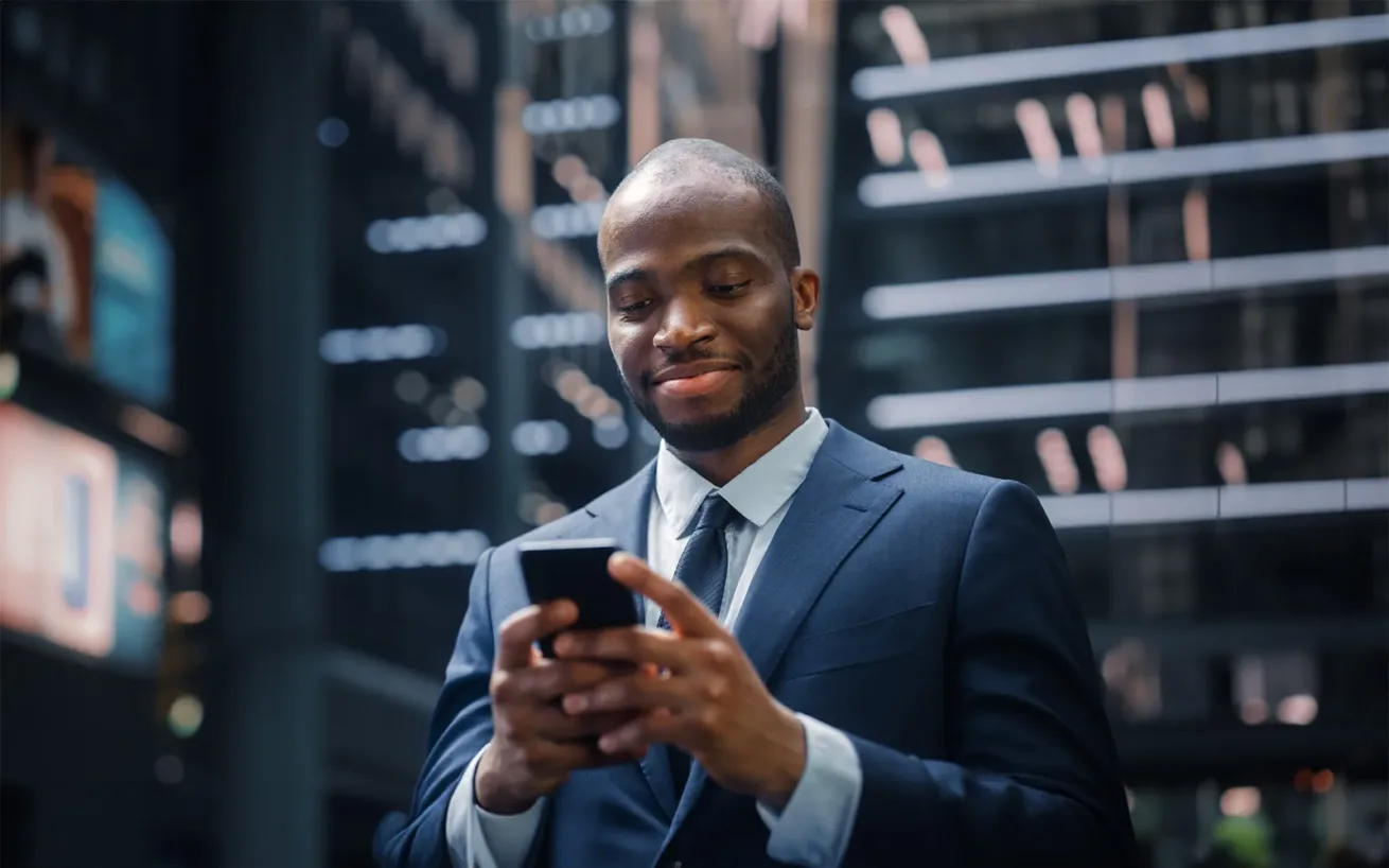 Portrait of Successful Businessman on the Street of the Central Business District in Big City. Digital Entrepreneur uses Mobile Phone e-Commerce App for Stock Market Investment