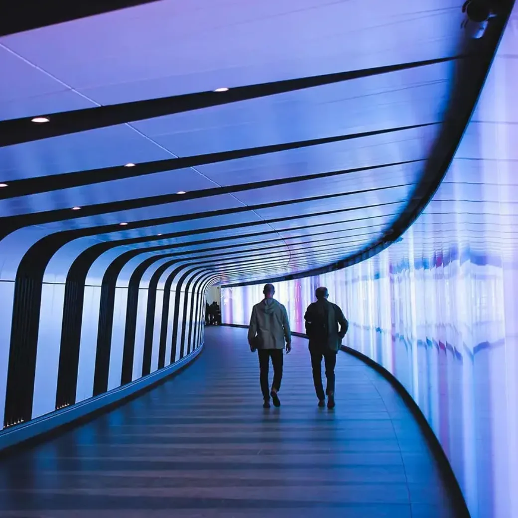 Zwei Personen laufen durch eine Unterführung mit blauen Lichtern