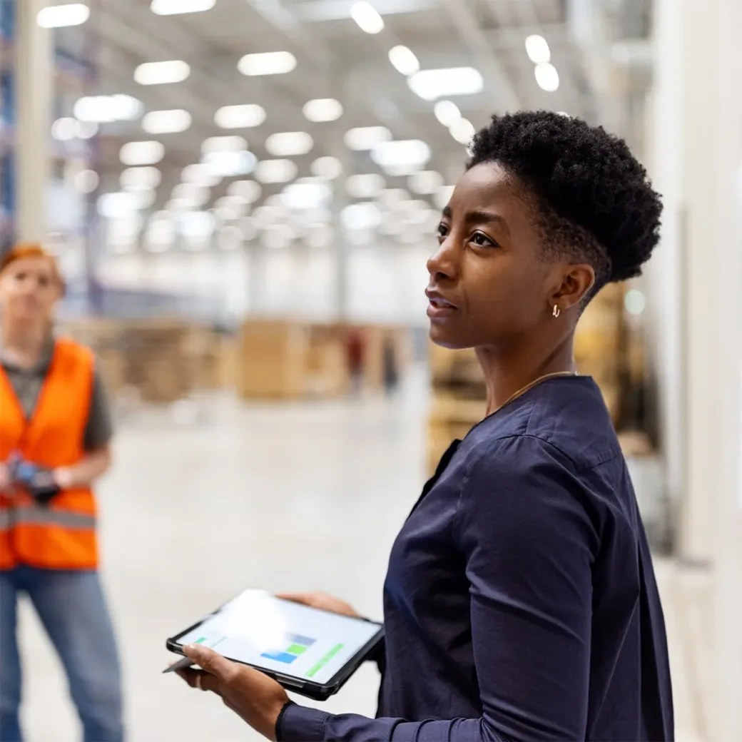 Supervisor standing by a whiteboard with a digital tablet discussing dispatch plan with workers. Team of workers having meeting in a distribution warehouse.