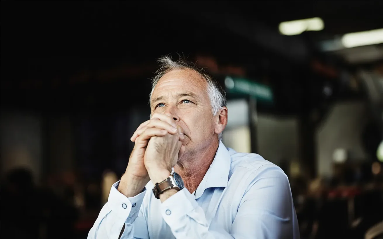 Ein Mann in eleganter Freizeitkleidung sitzt da und denkt über Lösungen nach.