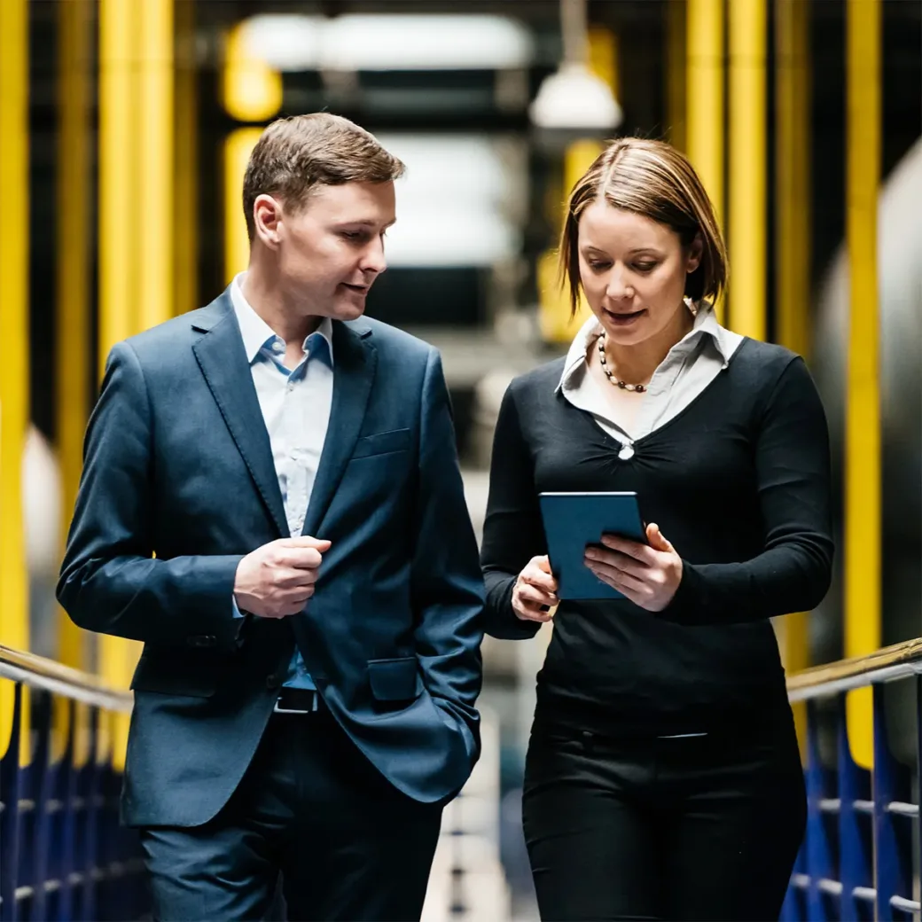 Two business people walking down a dark factory corridor