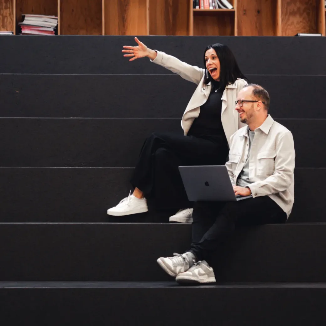 Three colleagues celebrate success in a modern office environment. Two people give each other a high-five while another person claps nearby.