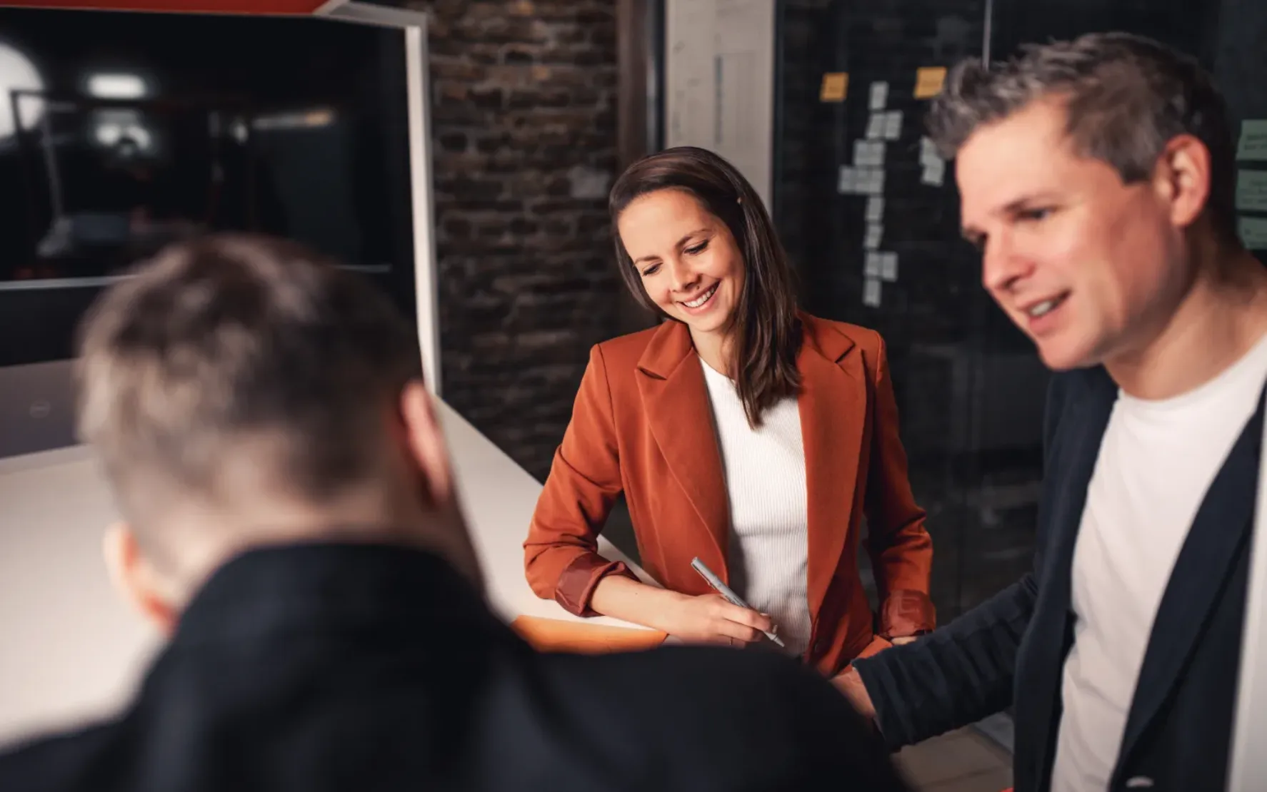 Foto von drei Grafikdesigner*innen, die an einem Konzept arbeiten