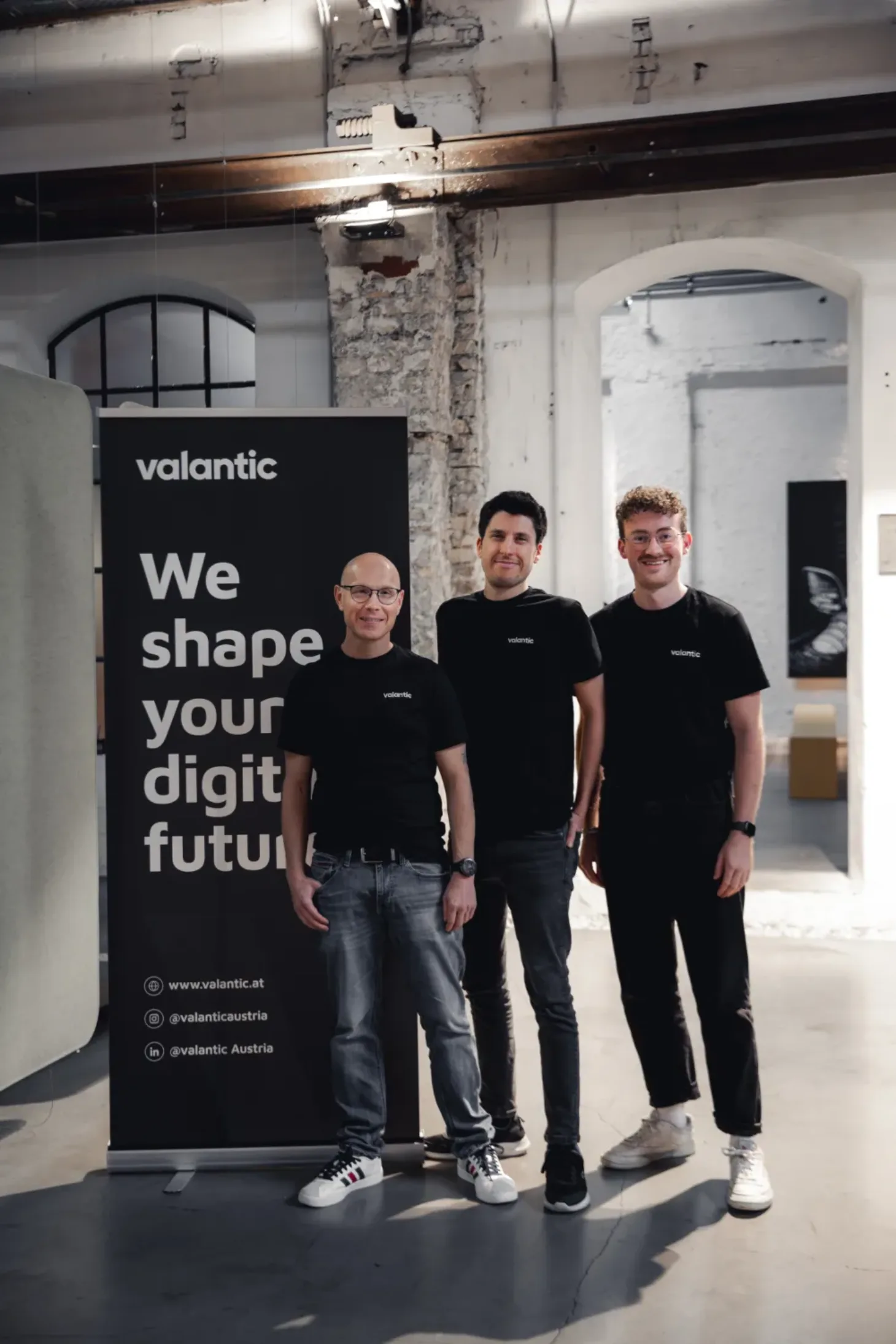 Drei Devs von valantic austria posieren neben einem RollUp auf dem 