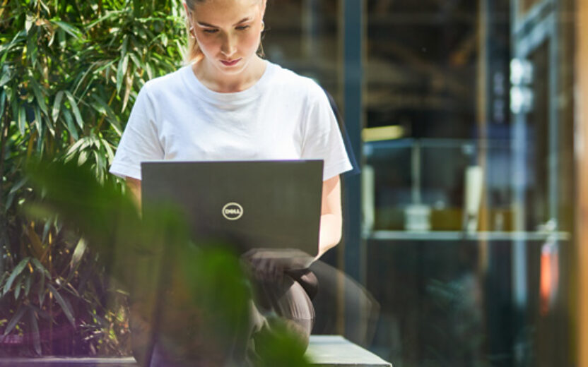 valantic Mitarbeiterin sitzt draußen an ihrem Laptop und arbeitet