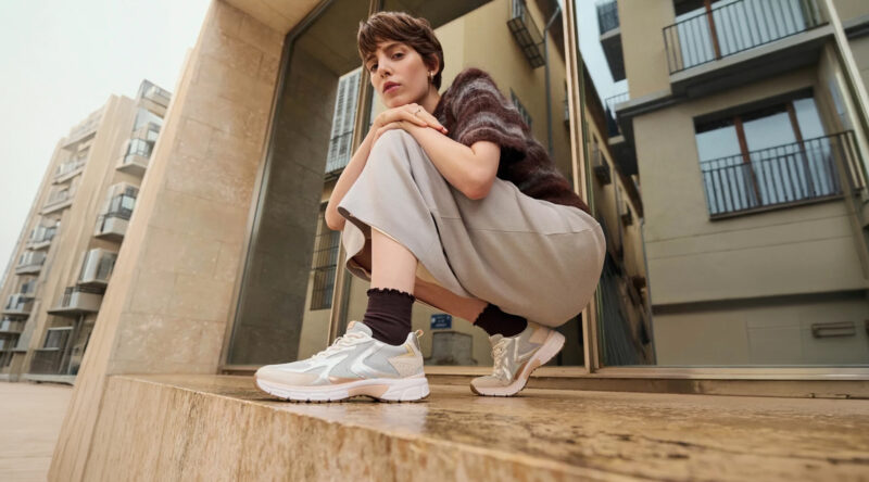 Frau sitzt vor einem Gebäude und trägt moderne Gabor Sneaker in urbaner Umgebung