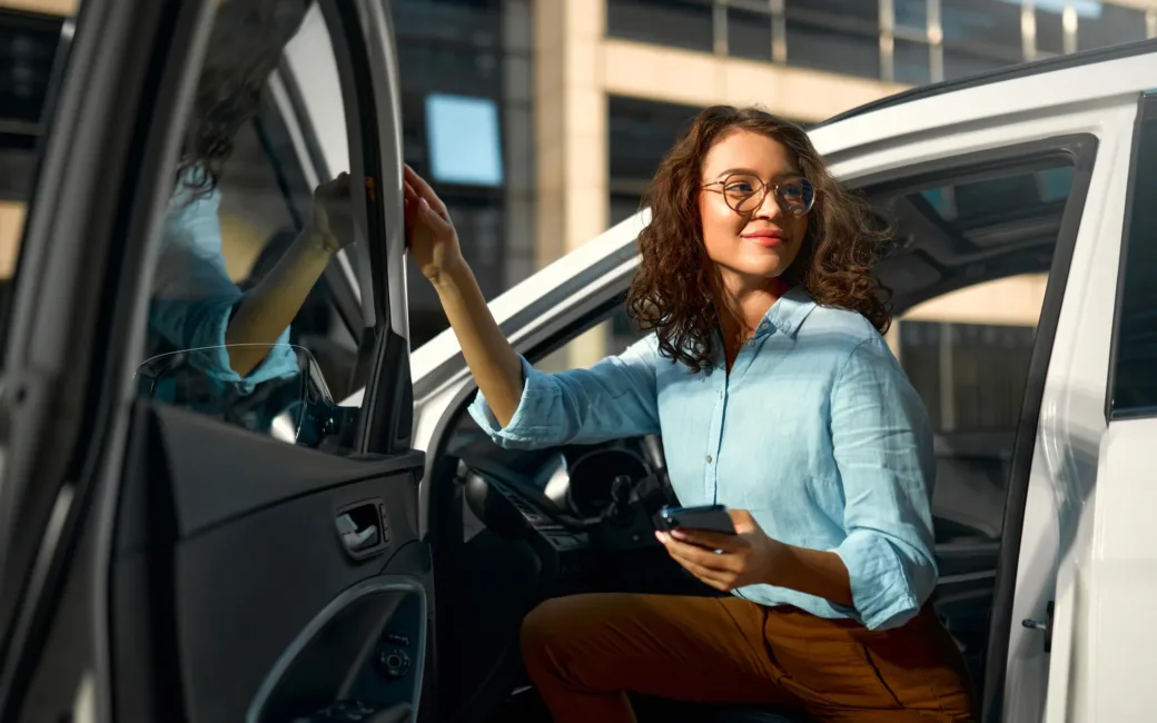 Business woman sitting in her new car and using smartphone.