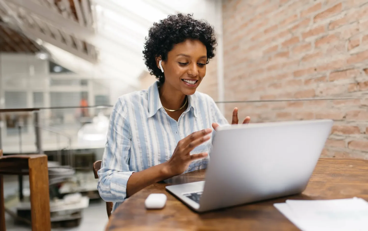 small business owner having an online meeting in a warehouse. Female entrepreneur video calling her business partners on a laptop. Happy businesswoman running an online startup.