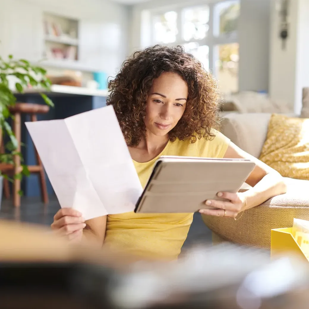 Woman reading on tablet and holding a letter with her other hand