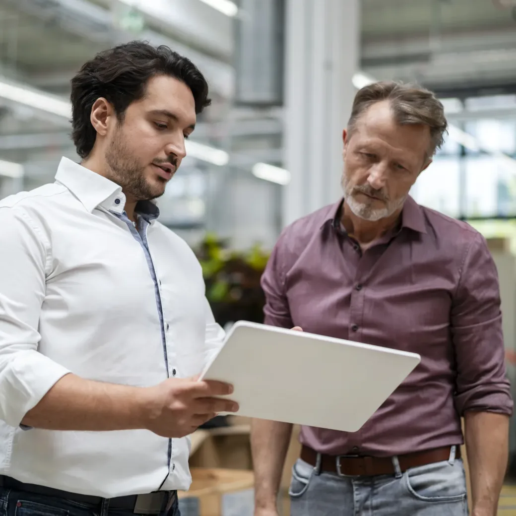 young-businessman-showing-tablet-PC-to-colleague-at-factory