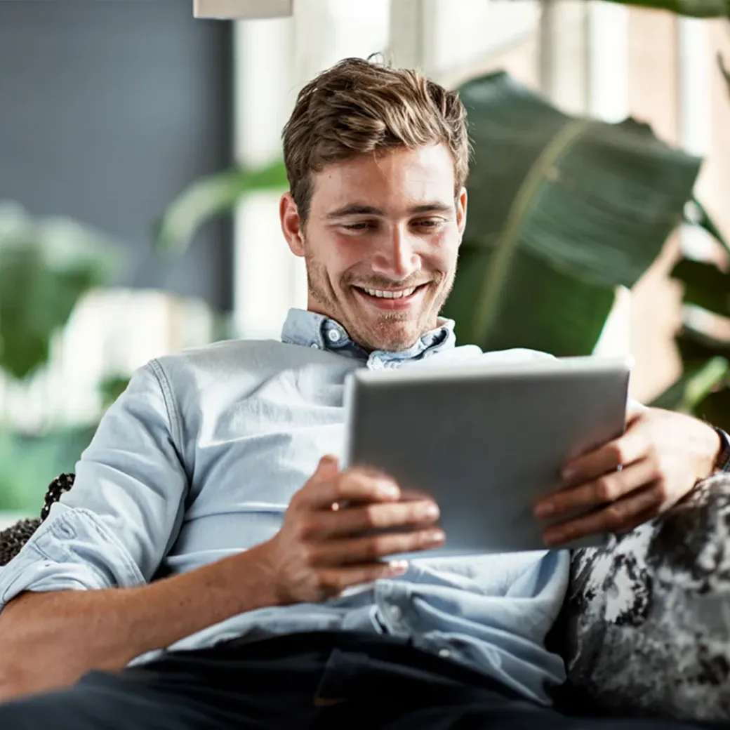 Shot of a happy young man using his tablet while relaxing on the couch at home